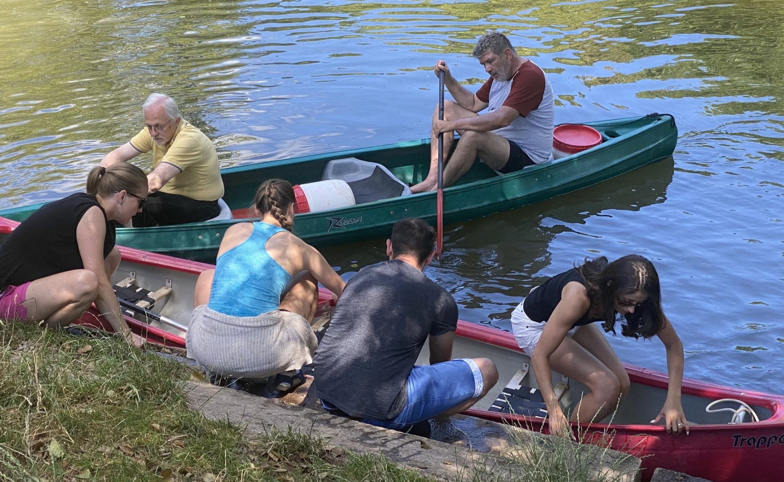 3 Männer und 3 Frauen am Wasser, die in ein Kanu einsteigen