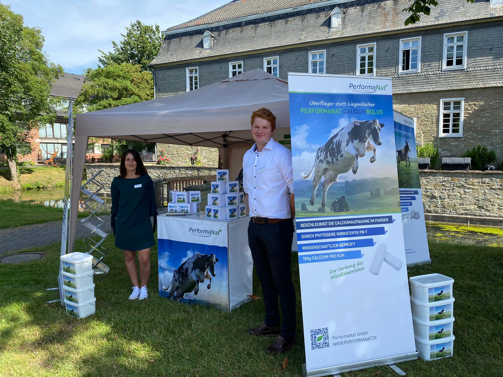 Eine Frau und ein Mann stehen vor einem Zelt mit PerformaNat Rollups